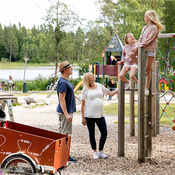 En familj med sina två döttrar i en lekpark