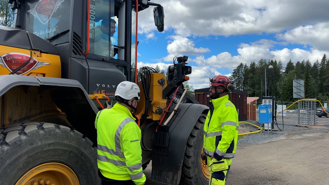 Personer pratar vid traktor