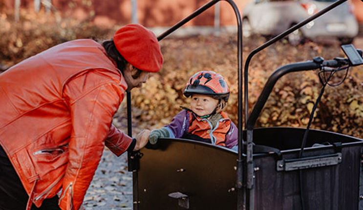 A dad stands by his child seated in a bicycle trailer